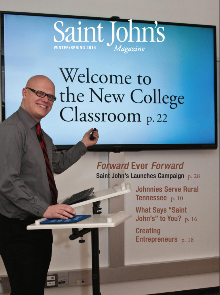 A person smiling and pointing at a large screen displaying "Welcome to the New College Classroom p. 22". The cover also mentions articles on "Saint John’s Launches Campaign" and "Creating Entrepreneurs".